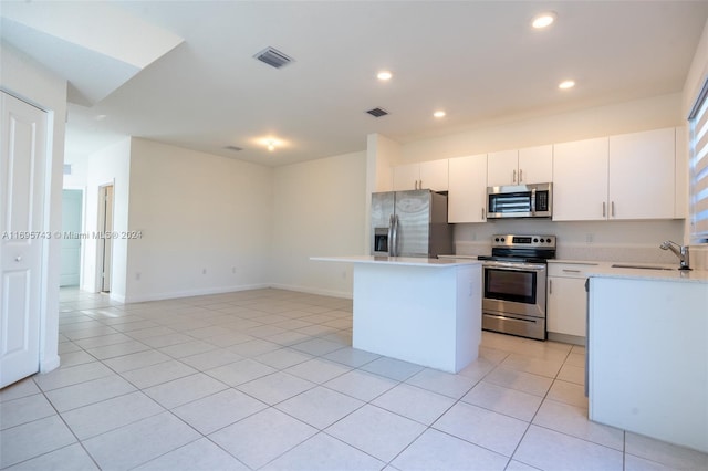 kitchen featuring a center island, sink, light tile patterned floors, white cabinetry, and stainless steel appliances