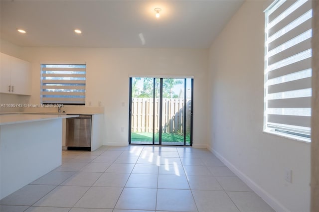 kitchen with dishwasher, light tile patterned floors, and white cabinetry