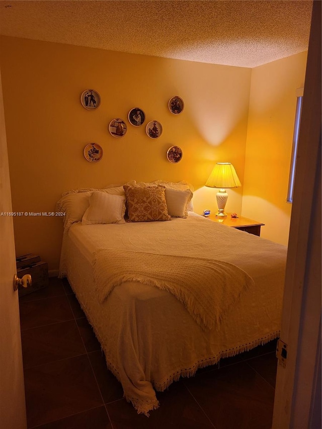 bedroom featuring dark tile patterned floors and a textured ceiling