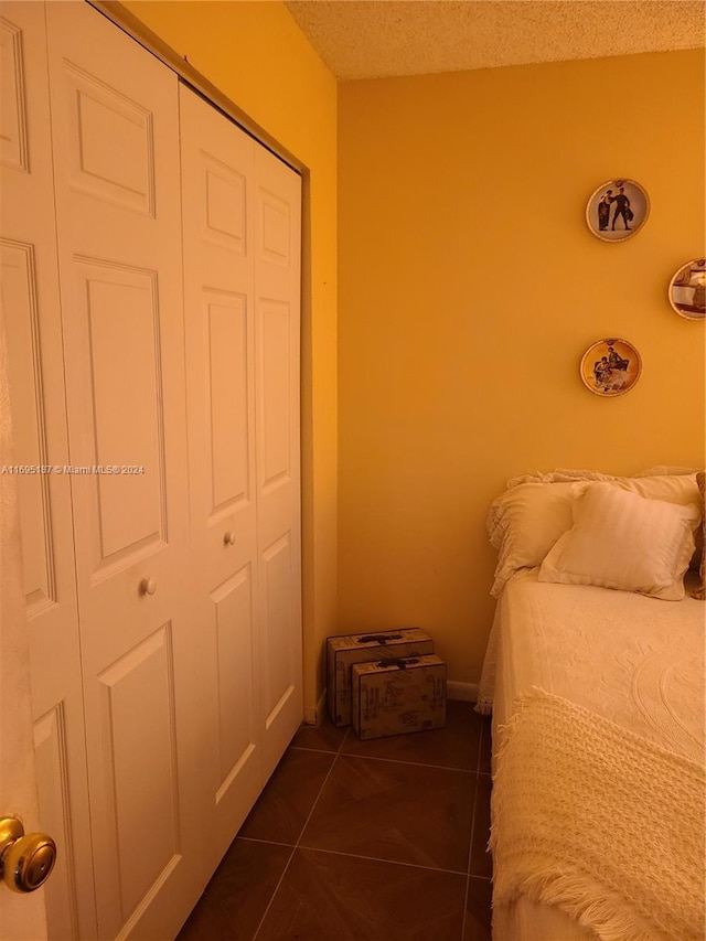 tiled bedroom with a closet and a textured ceiling