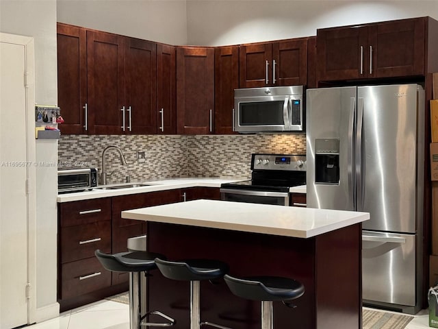 kitchen featuring sink, backsplash, a breakfast bar, a kitchen island, and appliances with stainless steel finishes