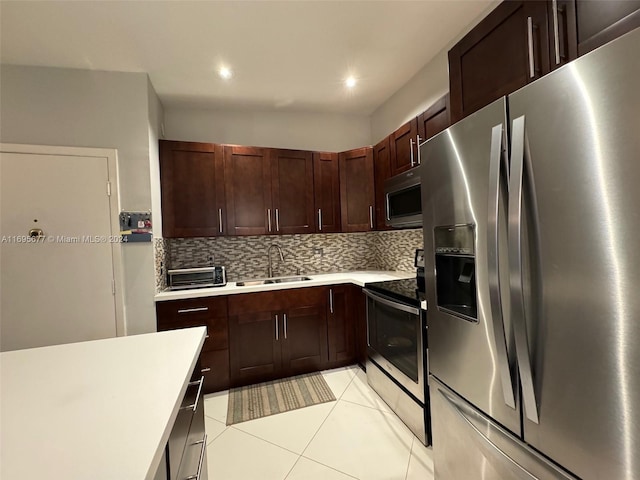 kitchen featuring backsplash, sink, light tile patterned floors, and appliances with stainless steel finishes