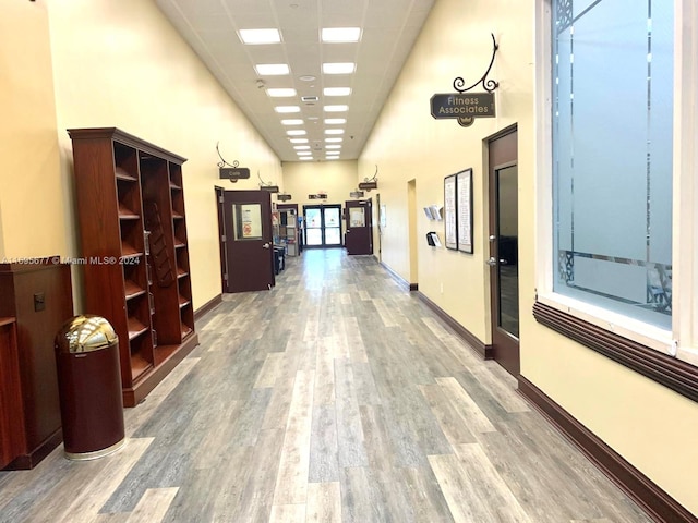 hallway featuring a towering ceiling, hardwood / wood-style flooring, and a drop ceiling