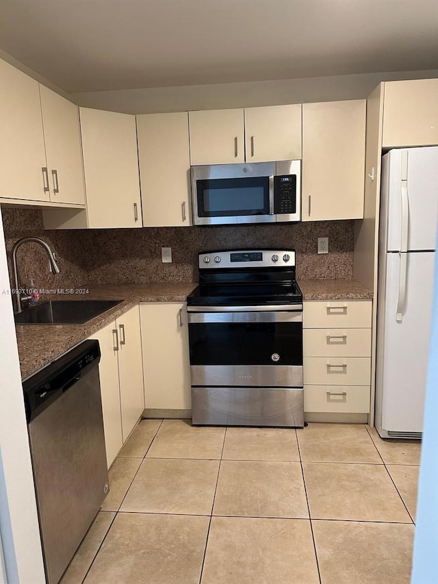 kitchen featuring decorative backsplash, light tile patterned floors, sink, and appliances with stainless steel finishes