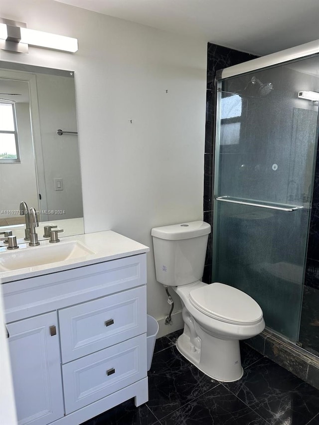 bathroom featuring a shower with door, vanity, and toilet