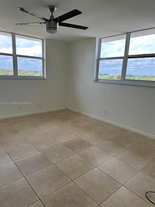 tiled spare room featuring a wealth of natural light and ceiling fan