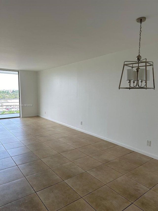 spare room with tile patterned floors and an inviting chandelier