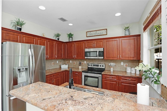 kitchen with stainless steel appliances, light stone counters, and tasteful backsplash