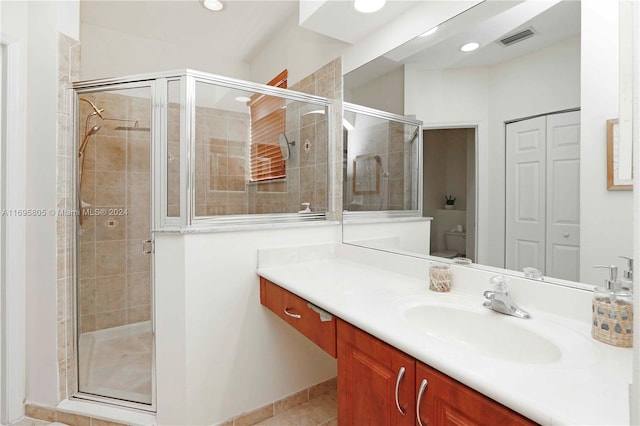 bathroom with tile patterned floors, a shower with door, vanity, and toilet