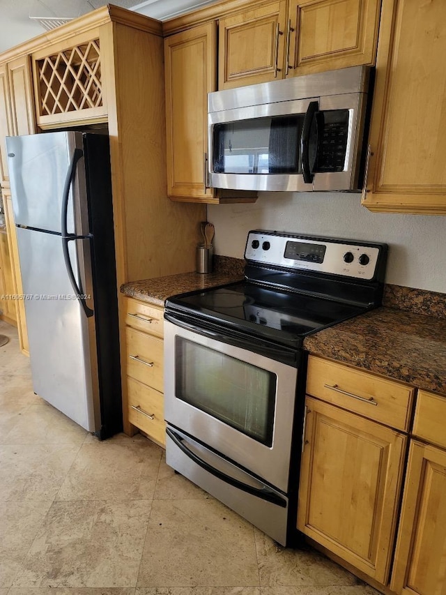 kitchen with appliances with stainless steel finishes and dark stone counters