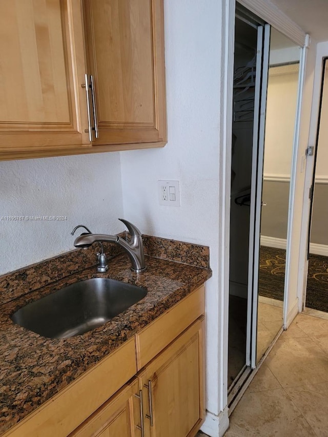 interior space with light tile patterned floors, sink, and dark stone counters