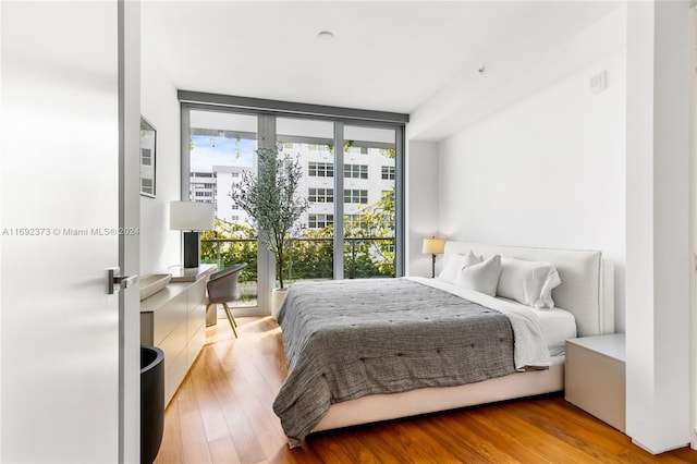 bedroom with light hardwood / wood-style floors, a wall of windows, and multiple windows