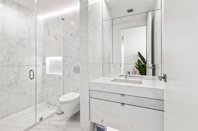 bathroom featuring vanity, toilet, a shower with door, and tile walls