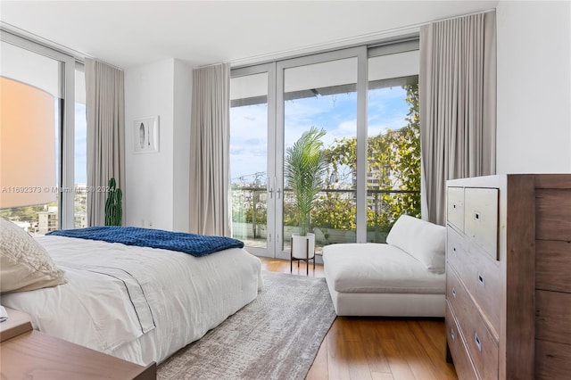 bedroom with expansive windows, access to outside, light hardwood / wood-style flooring, and multiple windows