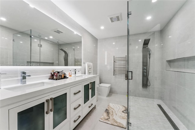 bathroom with walk in shower, vanity, tile walls, and toilet