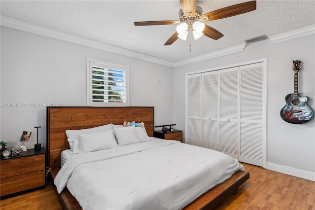 bedroom with ceiling fan, a closet, light hardwood / wood-style floors, and a textured ceiling