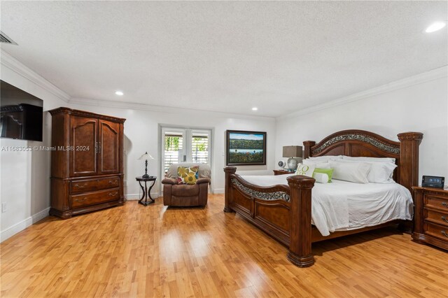 bedroom with a textured ceiling, light hardwood / wood-style flooring, and ornamental molding