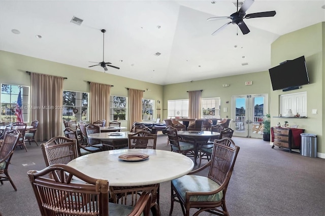 carpeted dining space with ceiling fan, french doors, and high vaulted ceiling