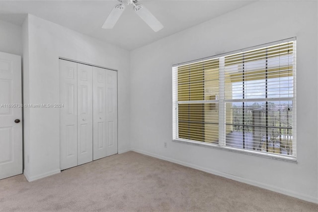 unfurnished bedroom with ceiling fan, light carpet, and a closet