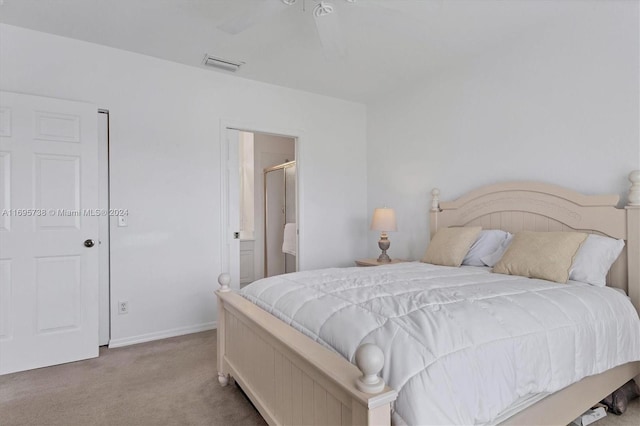 carpeted bedroom with ensuite bath and ceiling fan