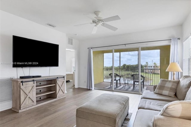 living room featuring hardwood / wood-style flooring, ceiling fan, and a water view