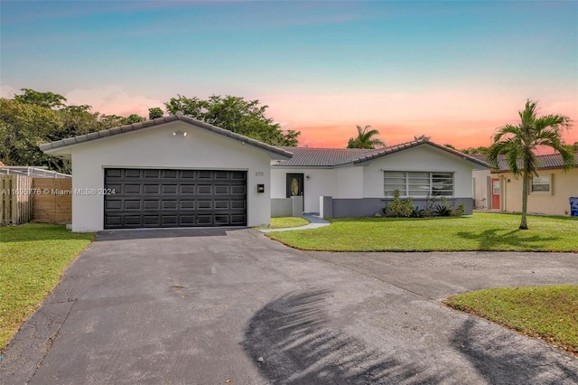 single story home with a garage and a yard