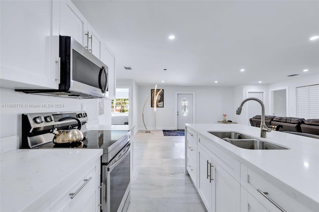 kitchen featuring appliances with stainless steel finishes, light stone counters, white cabinetry, and sink