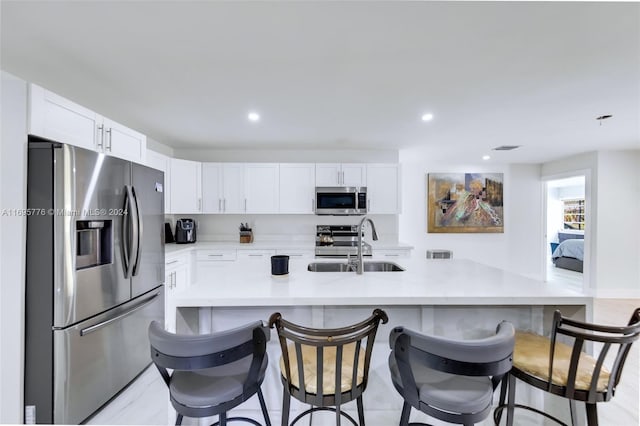 kitchen with white cabinets, sink, stainless steel appliances, and a breakfast bar area