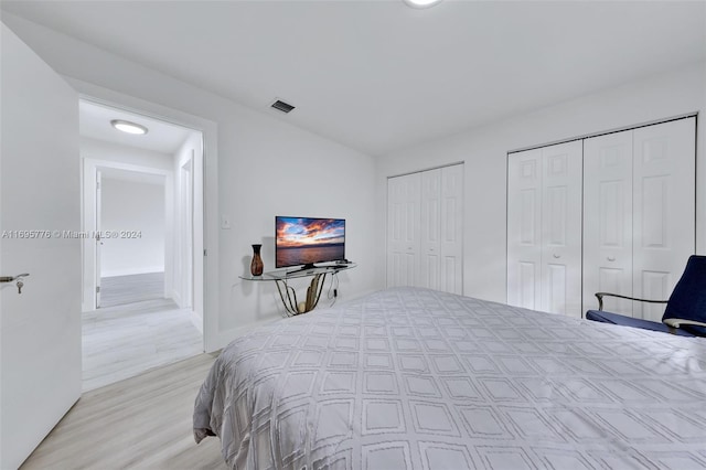 bedroom with light hardwood / wood-style flooring and two closets