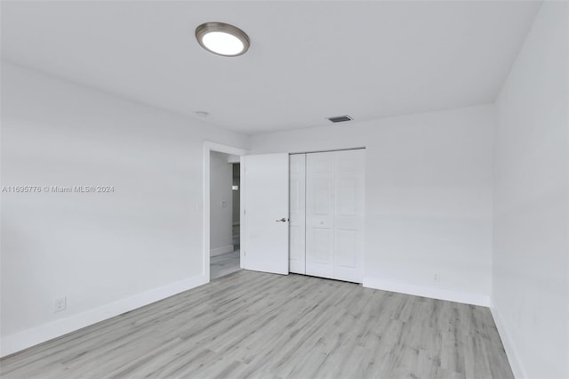 unfurnished bedroom with a closet and light wood-type flooring