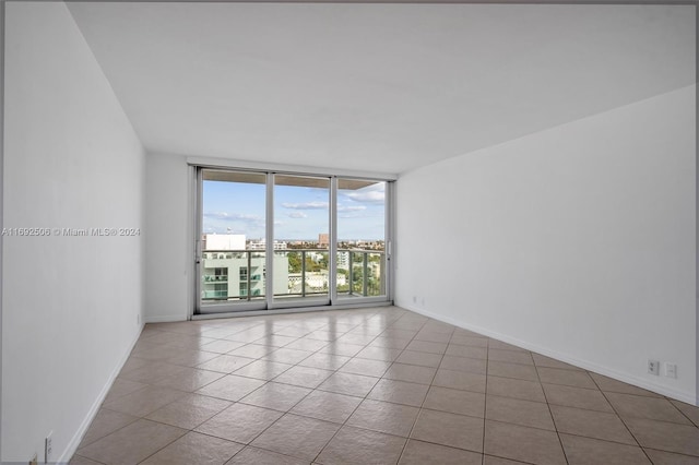 empty room with a wall of windows and light tile patterned floors