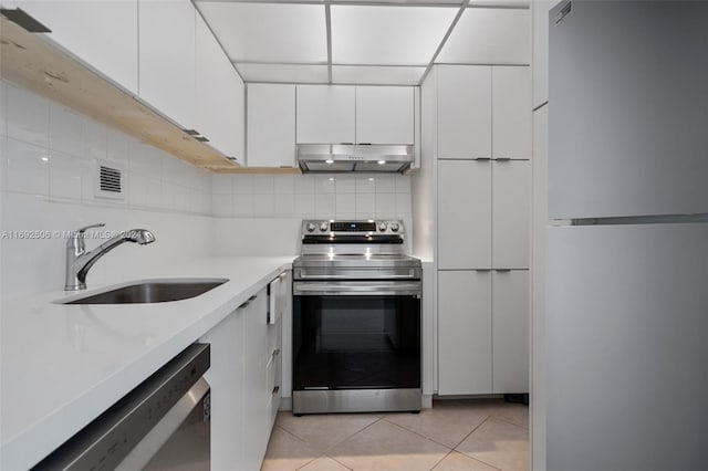 kitchen featuring tasteful backsplash, stainless steel appliances, sink, light tile patterned floors, and white cabinets