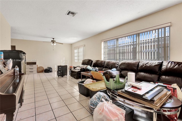 living room featuring ceiling fan, light tile patterned floors, and a textured ceiling