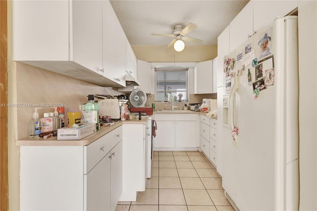 kitchen featuring white cabinetry, white fridge with ice dispenser, ceiling fan, sink, and a textured ceiling