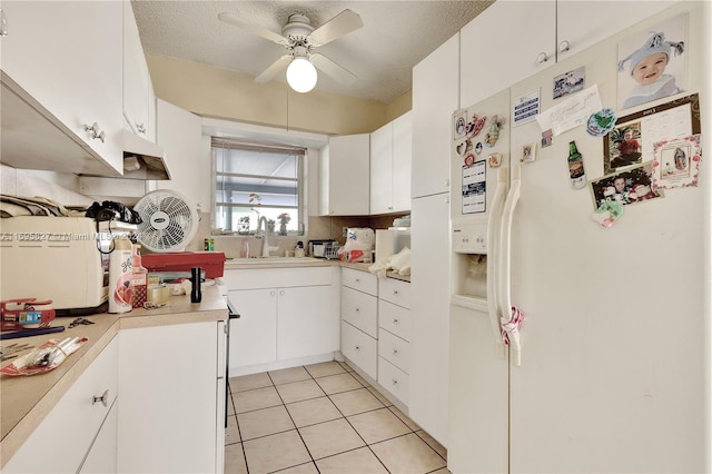 kitchen with white refrigerator with ice dispenser, white cabinets, sink, ceiling fan, and a textured ceiling