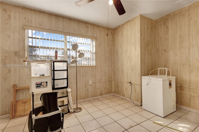 interior space featuring wooden walls, light tile patterned floors, and a textured ceiling