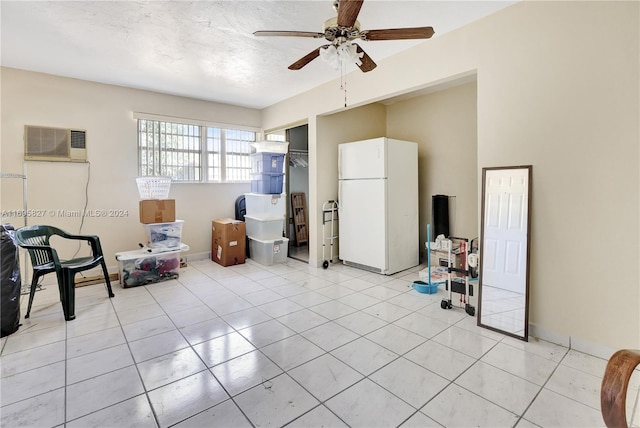 living area featuring a wall mounted AC, ceiling fan, light tile patterned floors, and a textured ceiling