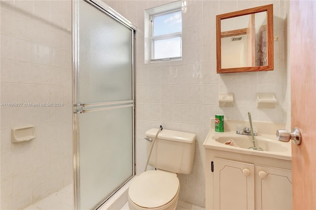 bathroom with an enclosed shower, vanity, toilet, and tile walls