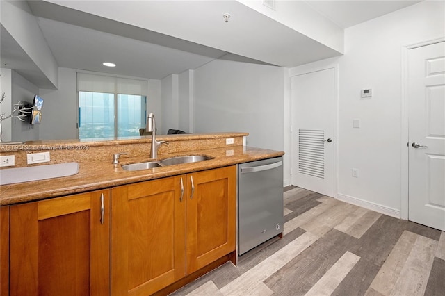 kitchen featuring stainless steel dishwasher, sink, and light hardwood / wood-style flooring