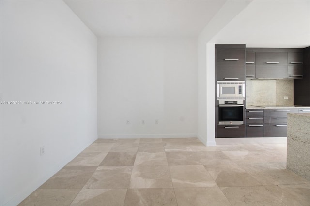 kitchen featuring decorative backsplash, appliances with stainless steel finishes, light stone counters, and light tile patterned flooring