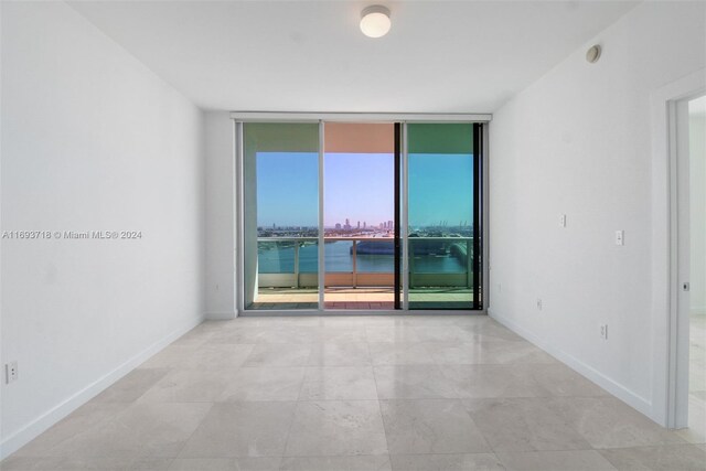 spare room featuring floor to ceiling windows and a water view