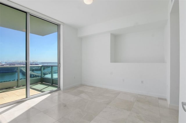 spare room with a water view and a wall of windows