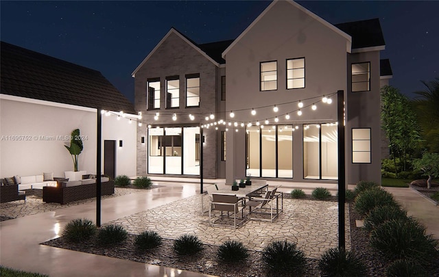 back house at twilight with outdoor lounge area and a patio area