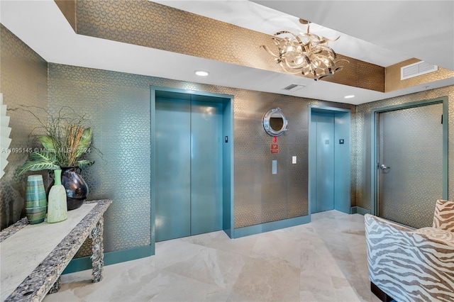 hallway with elevator and a chandelier