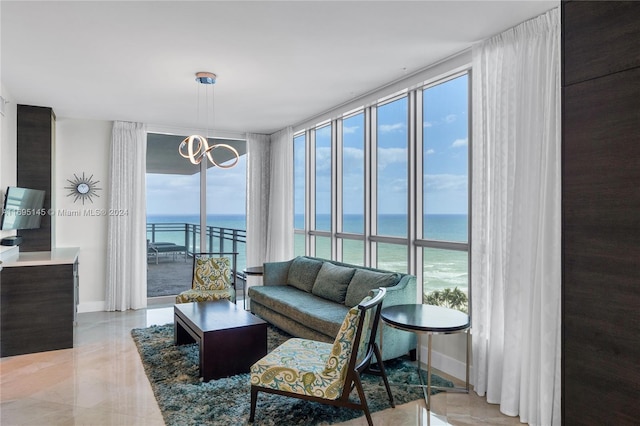 living room featuring a chandelier, light tile patterned floors, a water view, and a wall of windows