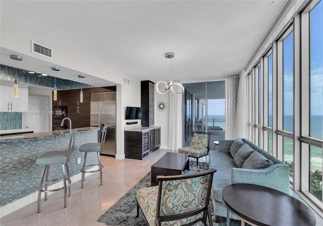 living room with expansive windows, a water view, and a chandelier