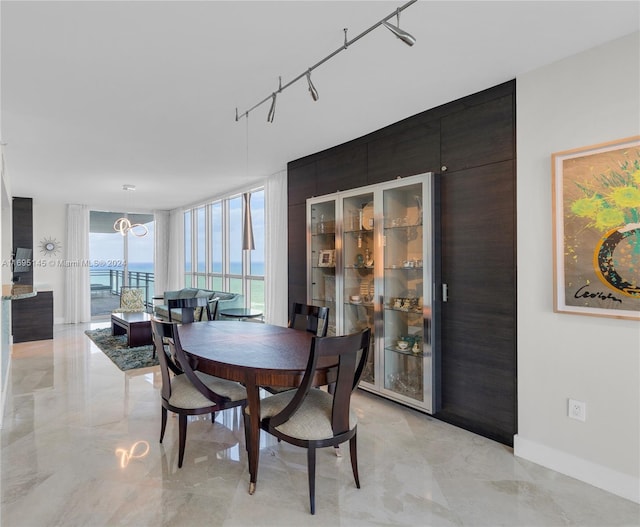 dining area with rail lighting, a water view, and floor to ceiling windows