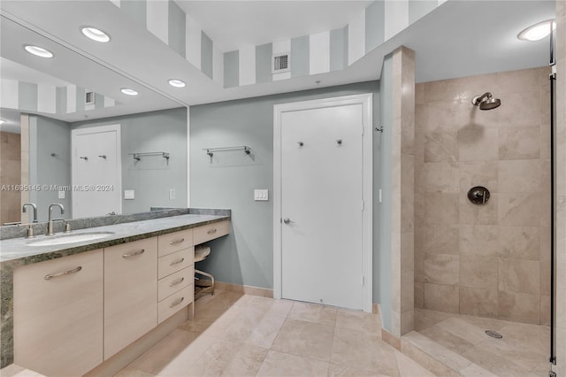 bathroom with tiled shower, vanity, and tile patterned flooring