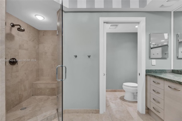 bathroom with tile patterned floors, vanity, a shower with shower door, and toilet