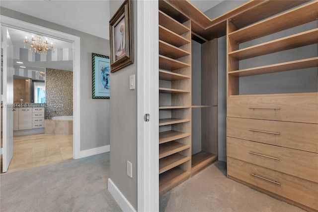 walk in closet featuring light carpet and a chandelier